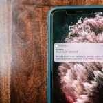 Smartphone exibindo um alerta de fraude sobre uma superfície de madeira.
