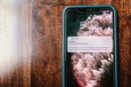 Smartphone exibindo um alerta de fraude sobre uma superfície de madeira.