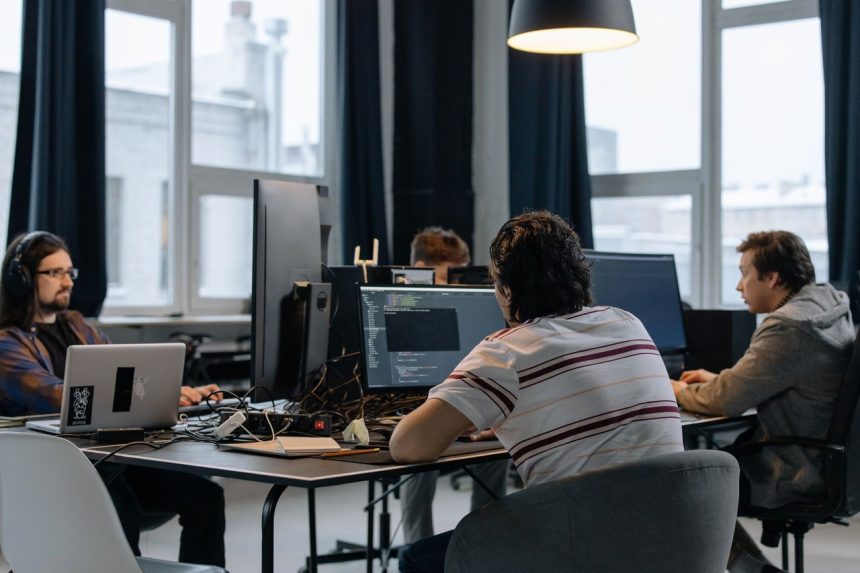 Equipe de desenvolvedores trabalha em computadores em um escritório moderno de tecnologia