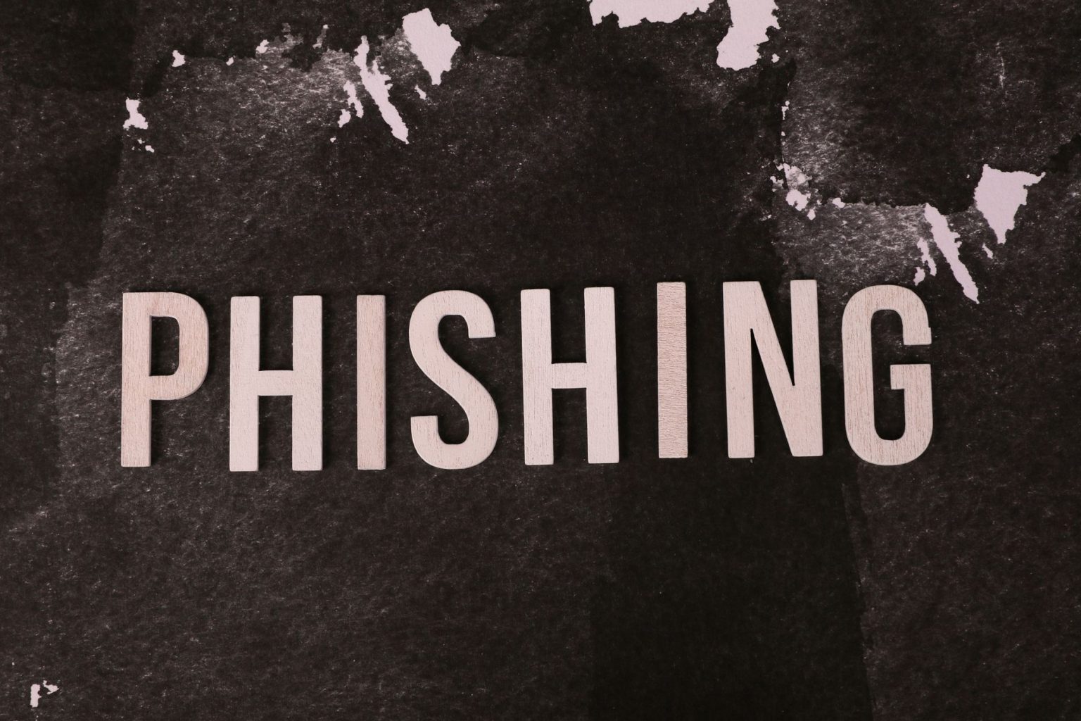 Composição abstrata sobre phishing, com a palavra “phishing” em uma superfície escura e texturizada.