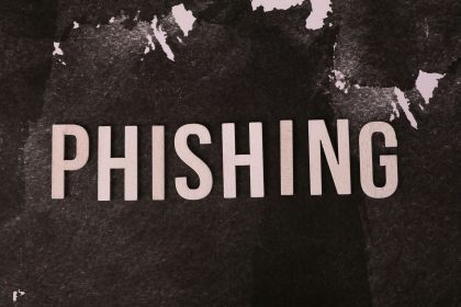 Composição abstrata sobre phishing, com a palavra “phishing” em uma superfície escura e texturizada.